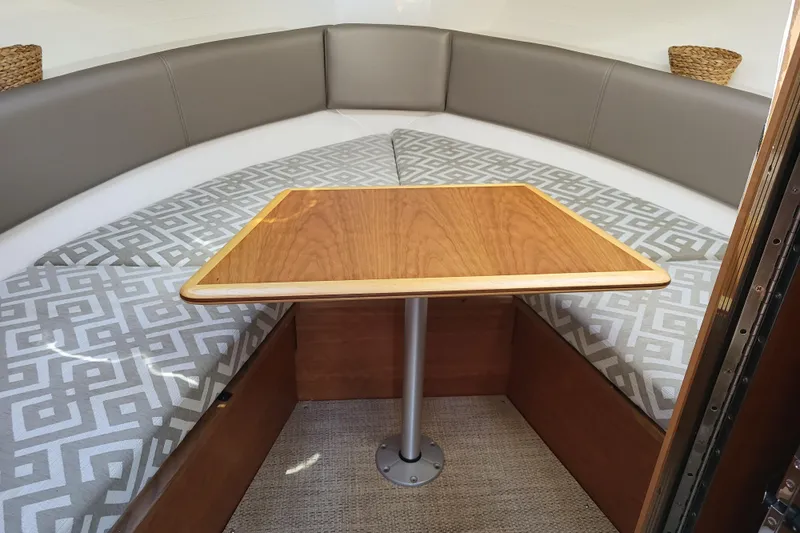 Tranquila Yacht Photos Pics 2023 Cutwater C-288 Coupe interior with cushioned seating and wooden table.