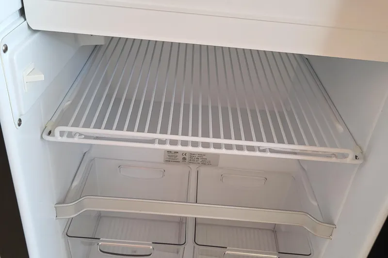 Tranquila Yacht Photos Pics Empty refrigerator interior with wire shelf and clear drawers in a 2023 Cutwater C-288 Coupe.