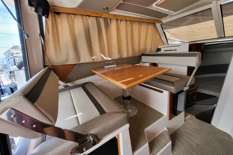 Tranquila Yacht Photos Pics 2023 Cutwater C-288 Coupe interior with dining area, cushioned seating, and wooden table.
