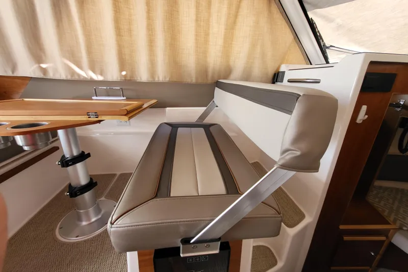Tranquila Yacht Photos Pics 2023 Cutwater C-288 Coupe interior with cushioned seating and wooden table.