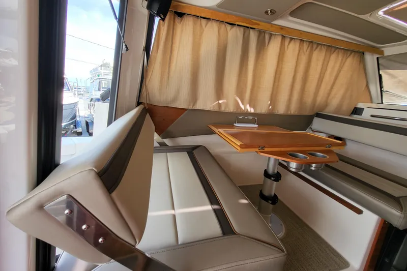 Tranquila Yacht Photos Pics 2023 Cutwater C-288 Coupe interior with beige seating and wooden table.