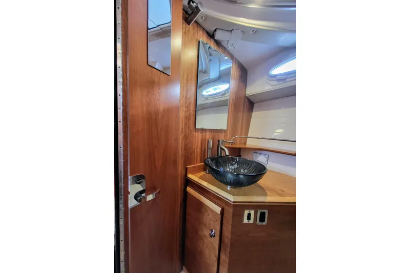 Tranquila Yacht Photos Pics 2023 Cutwater C-288 Coupe bathroom with wooden cabinetry and modern glass sink.