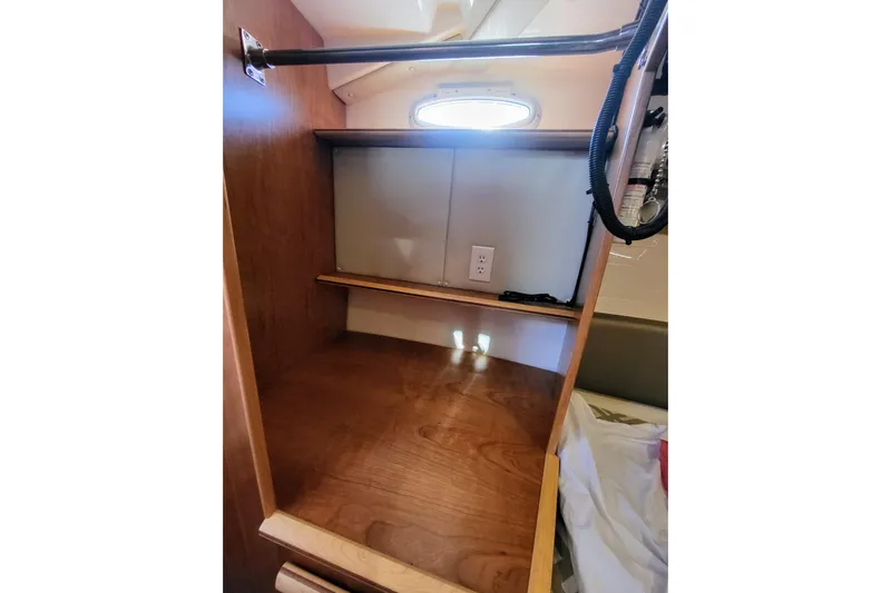 Tranquila Yacht Photos Pics 2023 Cutwater C-288 Coupe interior storage space with wooden finish and electrical outlet.