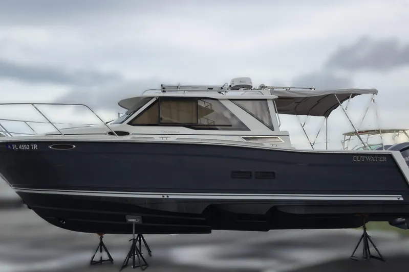 Tranquila Yacht Photos Pics 2023 Cutwater C-288 Coupe boat on stands, side view, overcast sky.