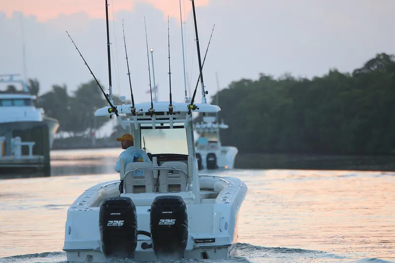  Yacht Photos Pics Manufacturer Provided Image: 2025 Boston Whaler 250 Outrage boat with fishing rods on a calm waterway at sunset.