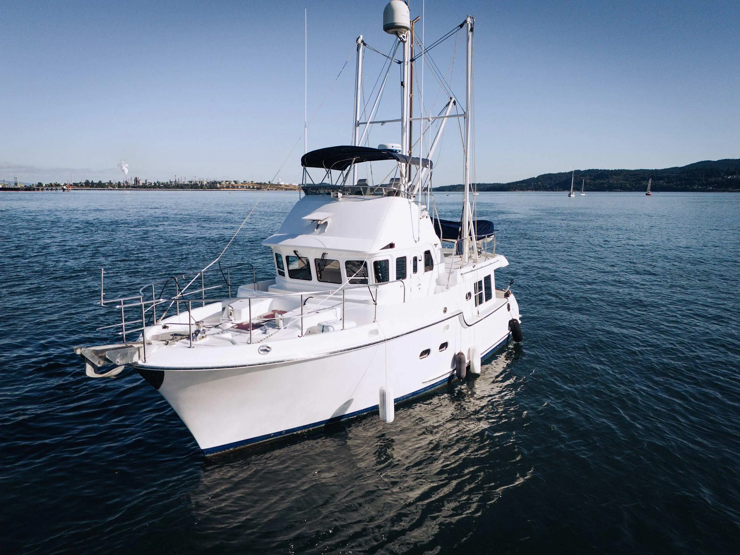 2004 Nordhavn 43 yacht on calm waters, clear sky, distant shoreline.