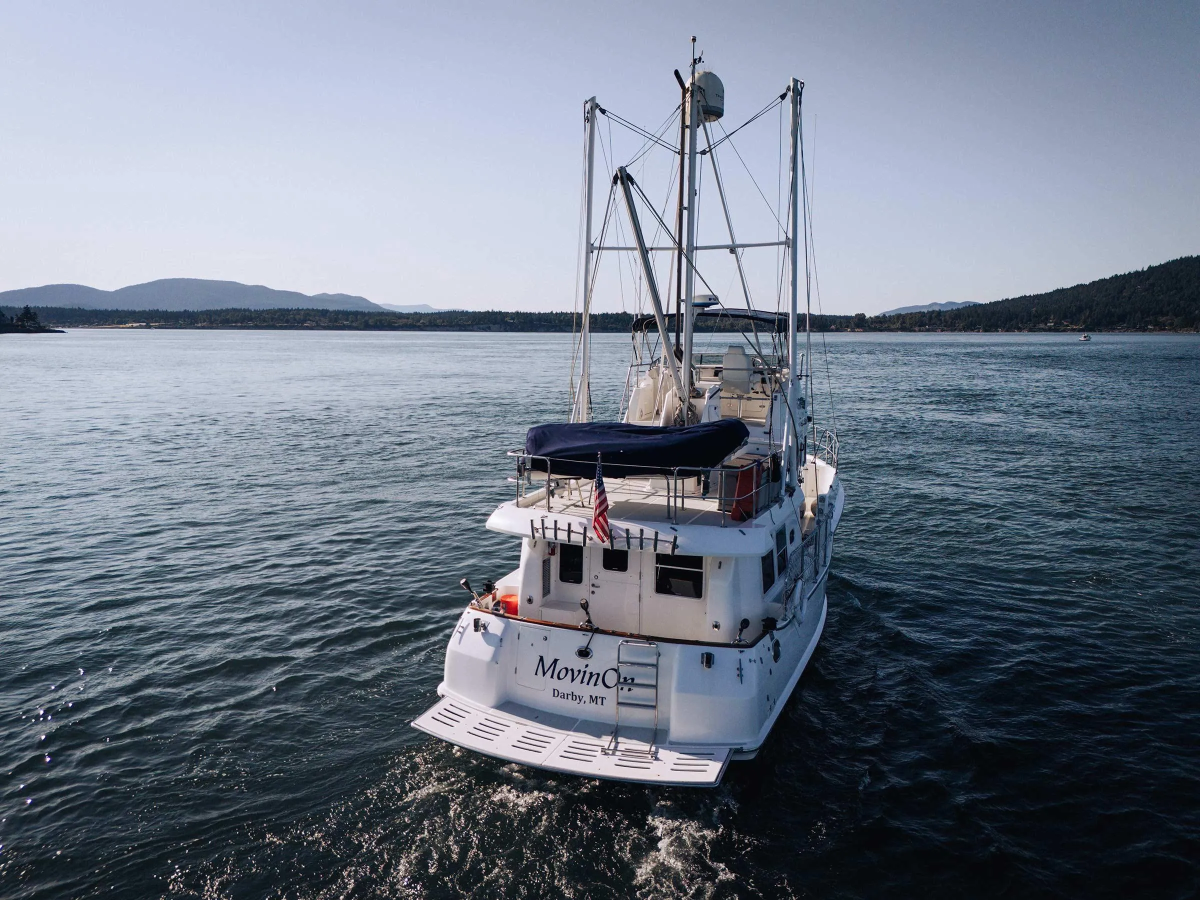 Nordhavn 43 yacht from 2004 cruising on a serene lake with mountainous backdrop.