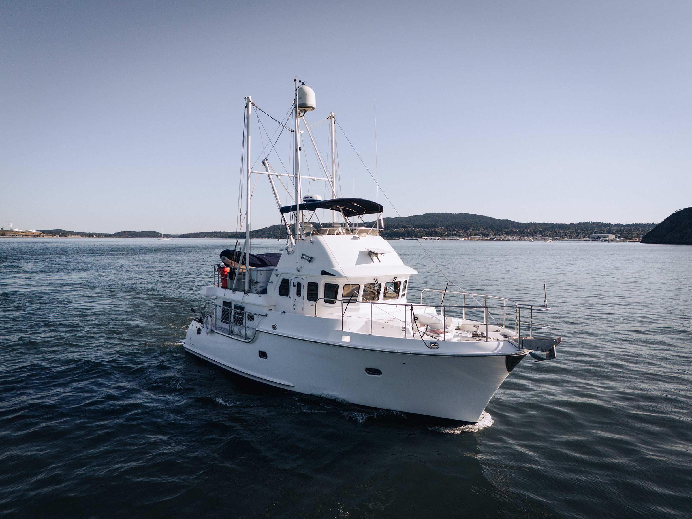 2004 Nordhavn 43 yacht cruising on calm waters with scenic coastline backdrop.