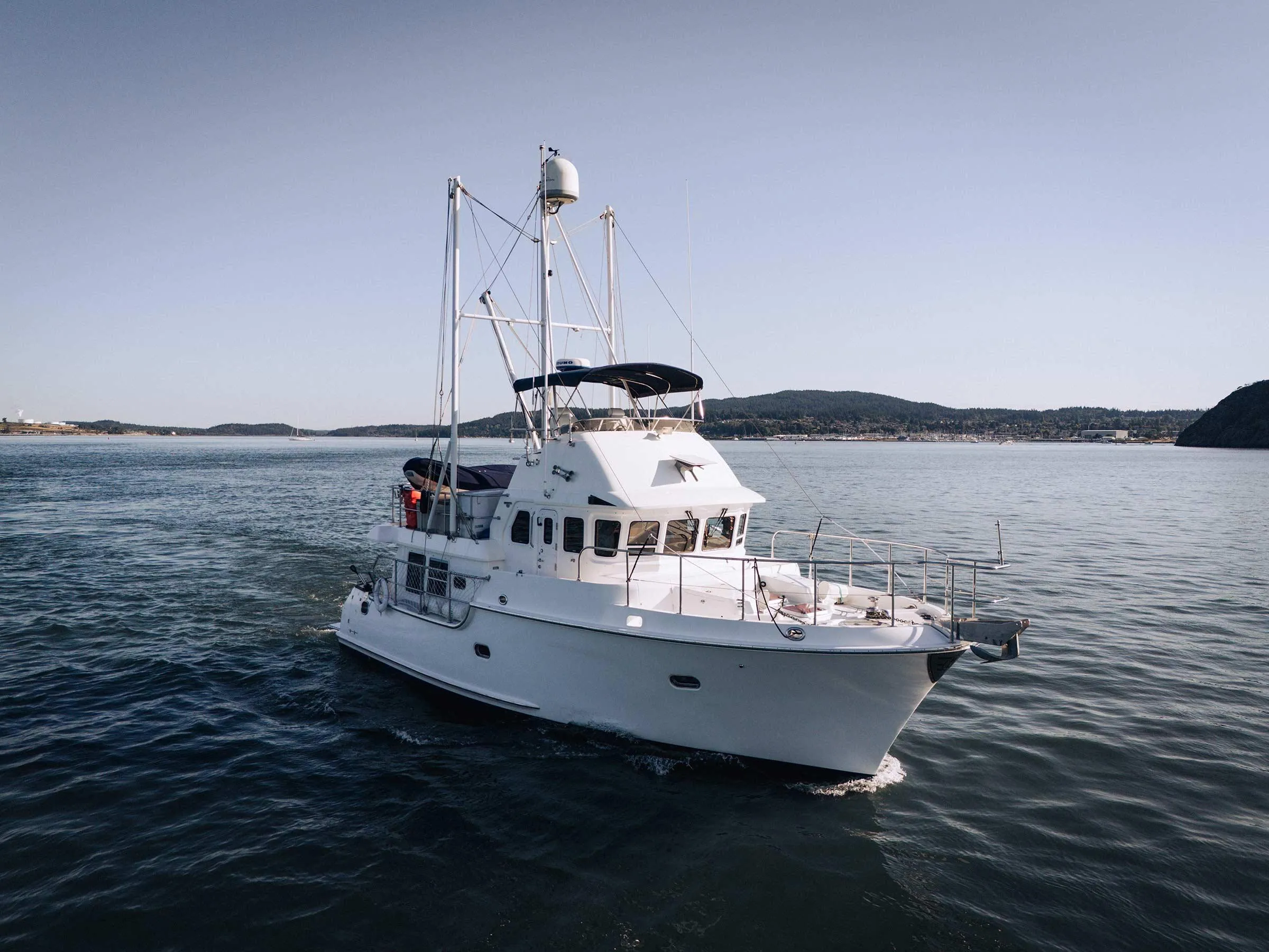 2004 Nordhavn 43 yacht cruising on calm waters with scenic coastline backdrop.