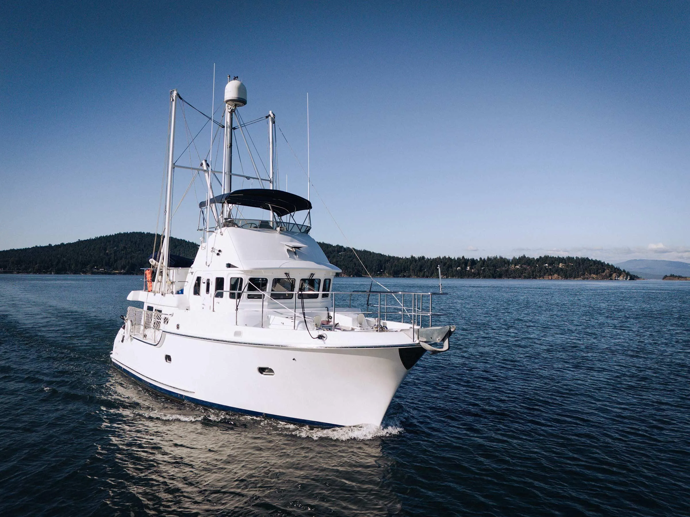 2004 Nordhavn 43 yacht cruising on calm waters with scenic island backdrop.