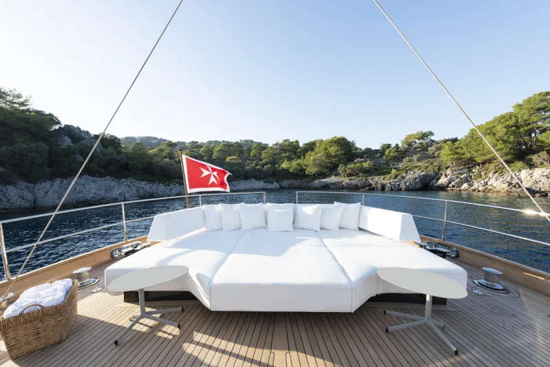 Atlantika Yacht Photos Pics Luxurious 2013 custom sailing yacht deck with white lounge, scenic coastal view, and red flag.