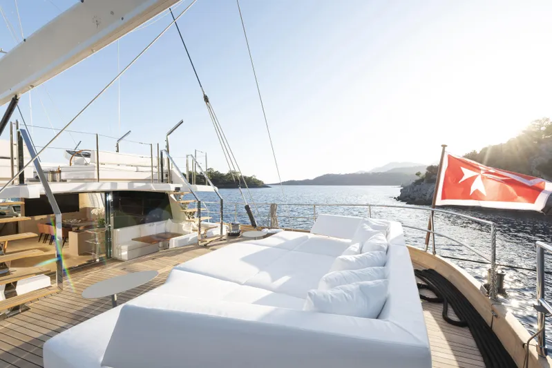 Atlantika Yacht Photos Pics Luxurious 2013 custom sailing yacht deck with white seating, scenic ocean view, and flag.