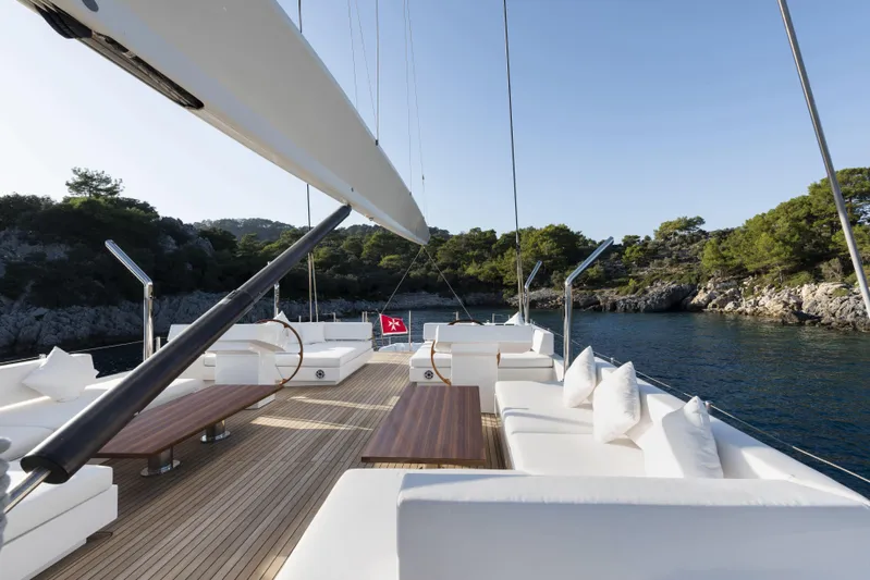 Atlantika Yacht Photos Pics Luxurious 2013 custom sailing yacht deck with white seating, wooden tables, and scenic coastal view.