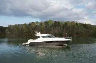 No Agenda Yacht Photos Pics 2016 Tiara Yachts C44 Coupe cruising on a serene lake with forested backdrop.