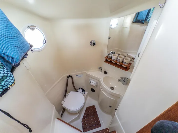  Yacht Photos Pics Compact bathroom in a 2018 Targa 27.1 boat with toilet, sink, and porthole.