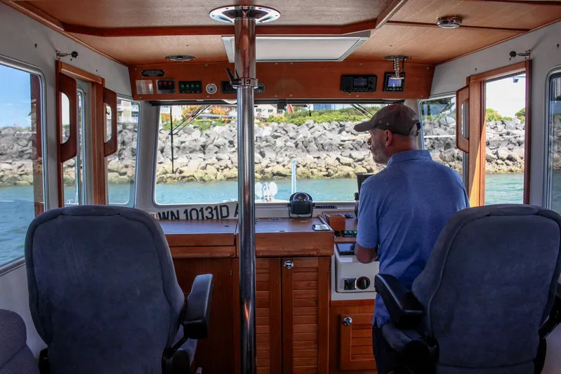  Yacht Photos Pics Man steering 2018 Targa 27.1 boat in a rocky coastal area.