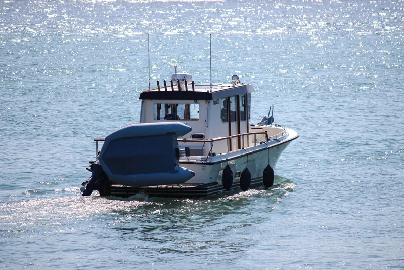  Yacht Photos Pics 2018 Targa 27.1 boat cruising on sparkling water with a small dinghy attached.