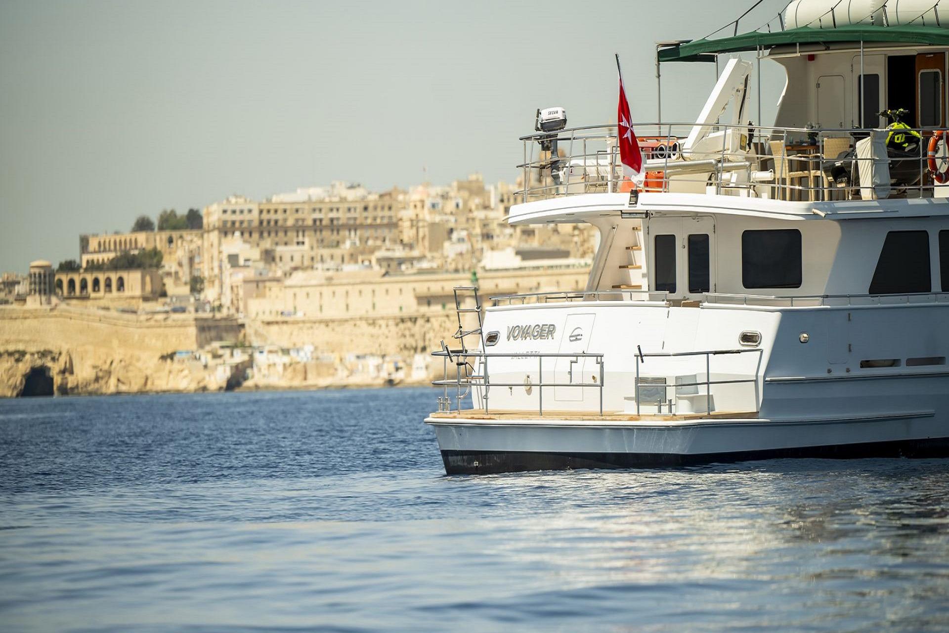 Explorer Seaton 85 yacht from 2004 on calm waters near historic coastal city.