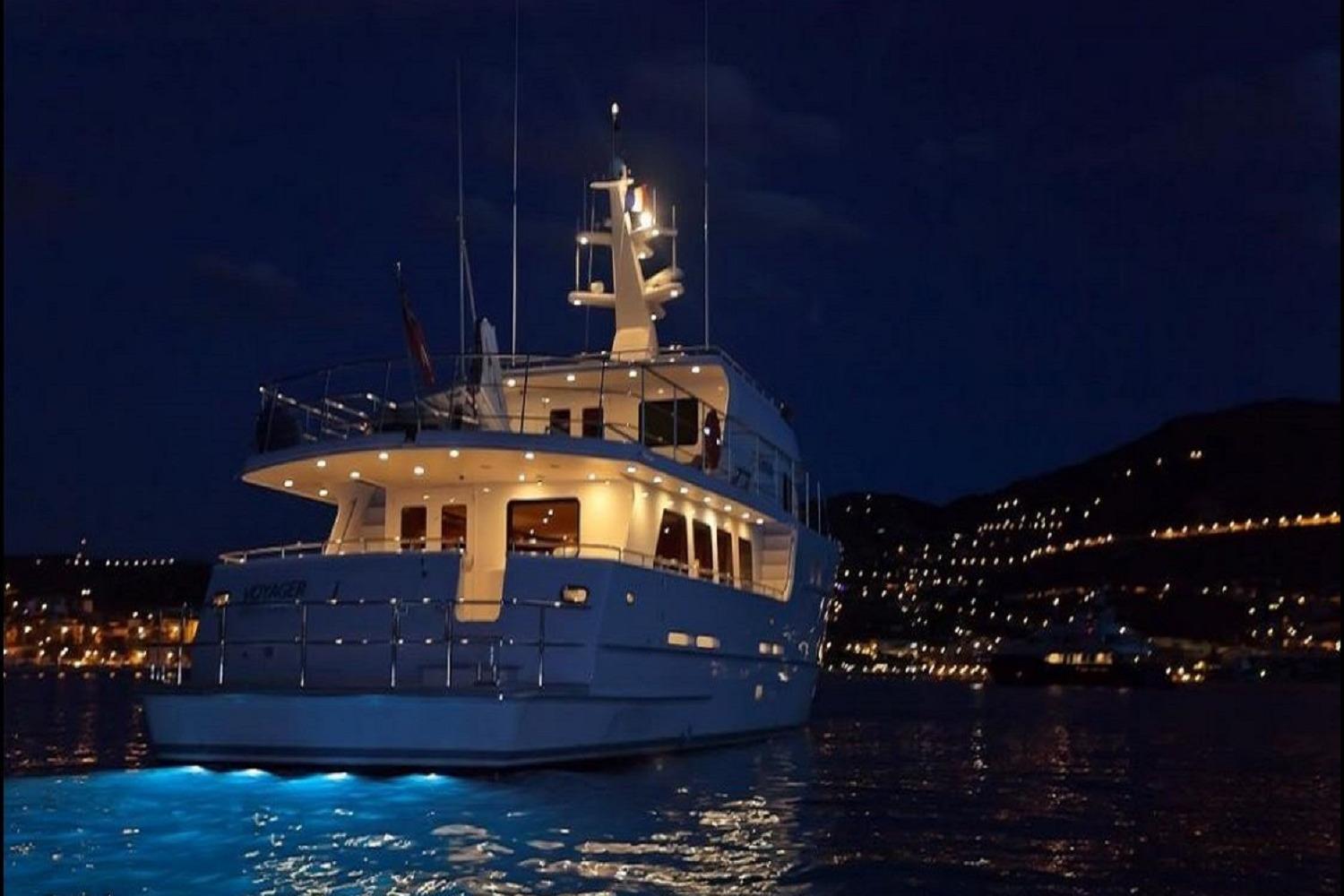Luxurious Explorer Seaton 85 yacht illuminated at night, 2004 model, on serene water.