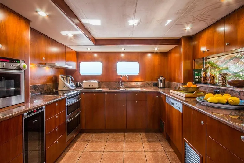  Yacht Photos Pics Luxurious yacht kitchen with wooden cabinetry, modern appliances, and fruit decor on Explorer Seaton 85, 2004.