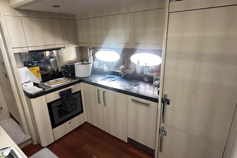  Yacht Photos Pics Compact kitchen in a 2006 Princess V70 yacht with modern appliances and wood cabinetry.