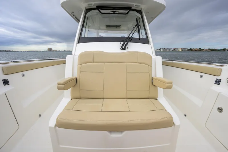  Yacht Photos Pics 2019 Pursuit S 328 Sport boat with beige seating, on calm waters under cloudy skies.