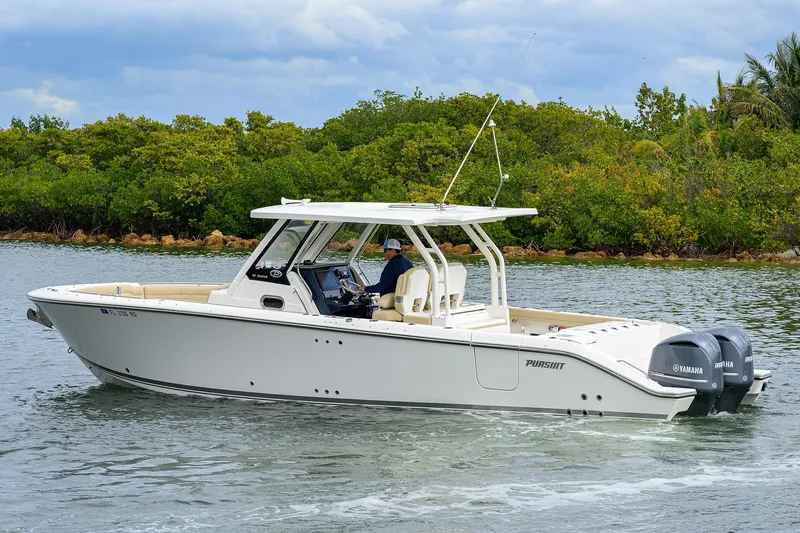  Yacht Photos Pics 2019 Pursuit S 328 Sport boat cruising on water with lush greenery background.