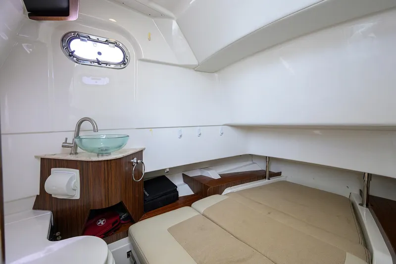 Yacht Photos Pics 2019 Pursuit S 328 Sport cabin interior with sink, bed, and porthole window.