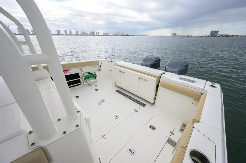  Yacht Photos Pics 2019 Pursuit S 328 Sport boat deck with dual engines, overlooking calm waters and city skyline.