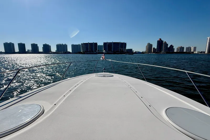 Island Time II Yacht Photos Pics Bow view of 2005 Four Winns 378 Vista yacht cruising near city skyline.