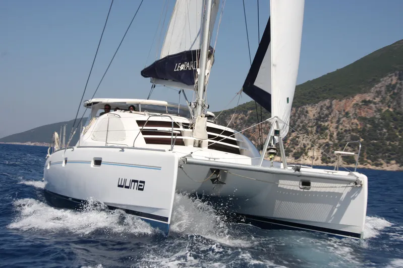  Yacht Photos Pics 2007 Leopard 40 catamaran sailing on open sea near rocky coastline.