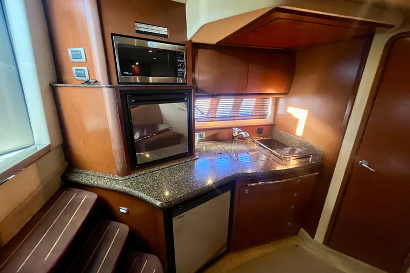  Yacht Photos Pics 2007 Sea Ray 38 Sundancer yacht interior kitchen with microwave, sink, and wooden cabinetry.