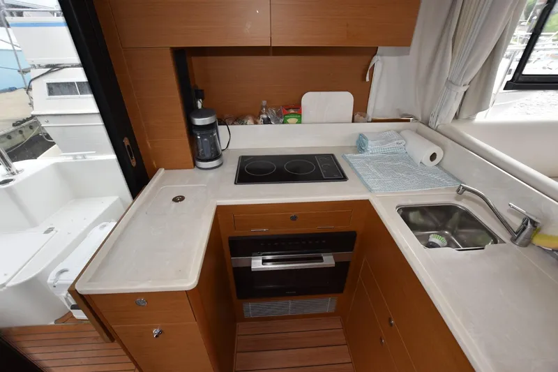  Yacht Photos Pics 2023 Beneteau Swift Trawler 41 Fly kitchen with stove, sink, and wooden cabinetry.
