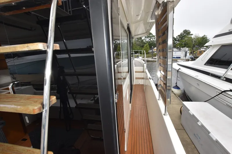  Yacht Photos Pics 2023 Beneteau Swift Trawler 41 Fly, side deck view with wooden steps and marina background.