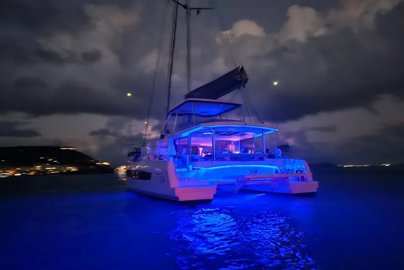 High 5 Yacht Photos Pics 2024 Bali 5.4 catamaran illuminated at night with vibrant blue lights on the water.