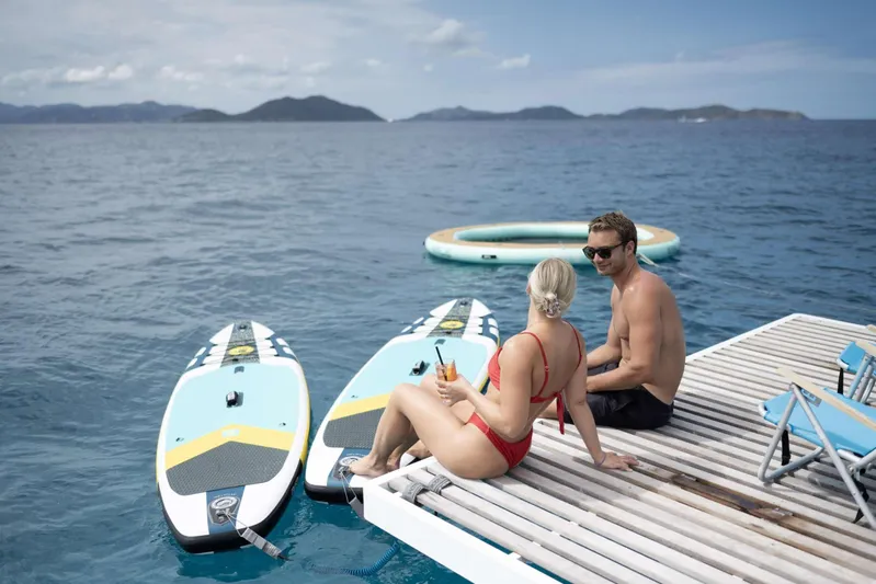 High 5 Yacht Photos Pics Couple relaxing on a dock with paddleboards, enjoying a sunny day on the water.