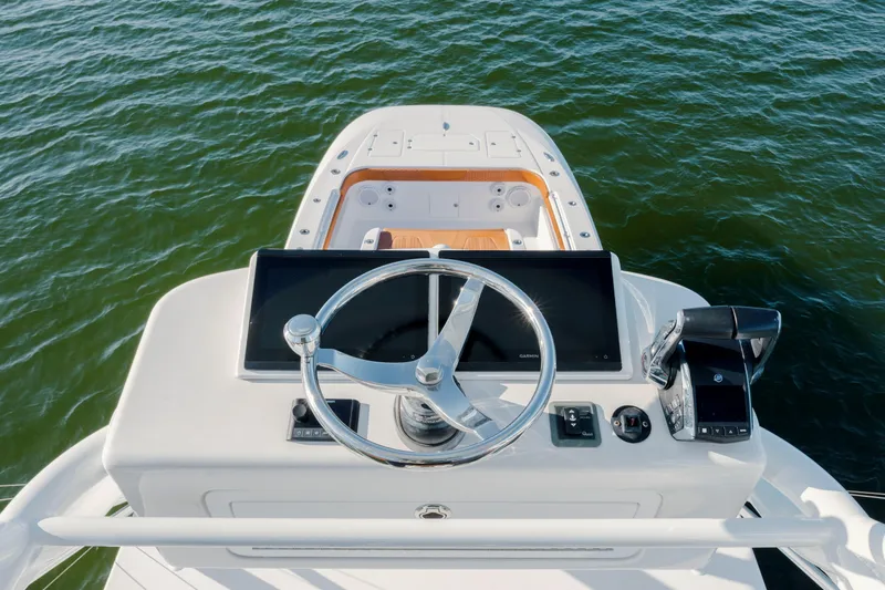 Yacht Photos Pics 2024 Invincible 46 Pilothouse helm with steering wheel and navigation screens on open water.