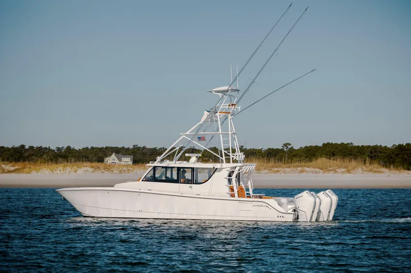  Yacht Photos Pics 2024 Invincible 46 Pilothouse boat on water near sandy shoreline.