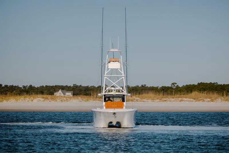  Yacht Photos Pics 2024 Invincible 46 Pilothouse boat cruising near sandy shoreline.