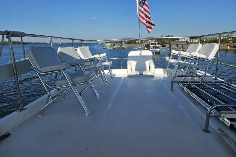  Yacht Photos Pics Deck of 2003 Johnson FLY boat with chairs and American flag, overlooking water.