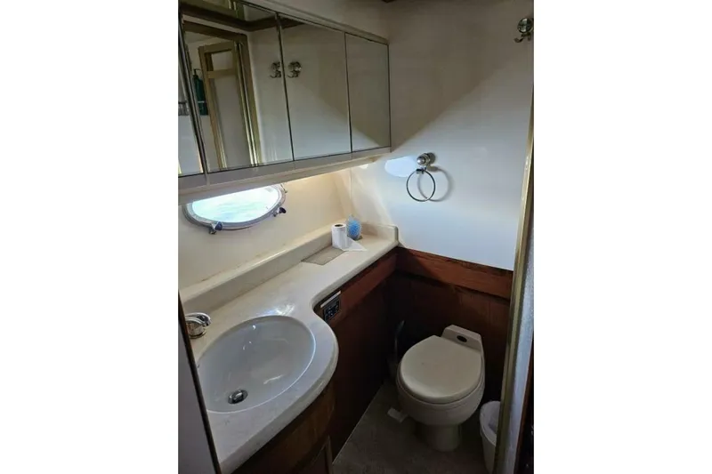  Yacht Photos Pics Compact bathroom in 2003 Johnson FLY boat with sink, toilet, and mirrored cabinets.