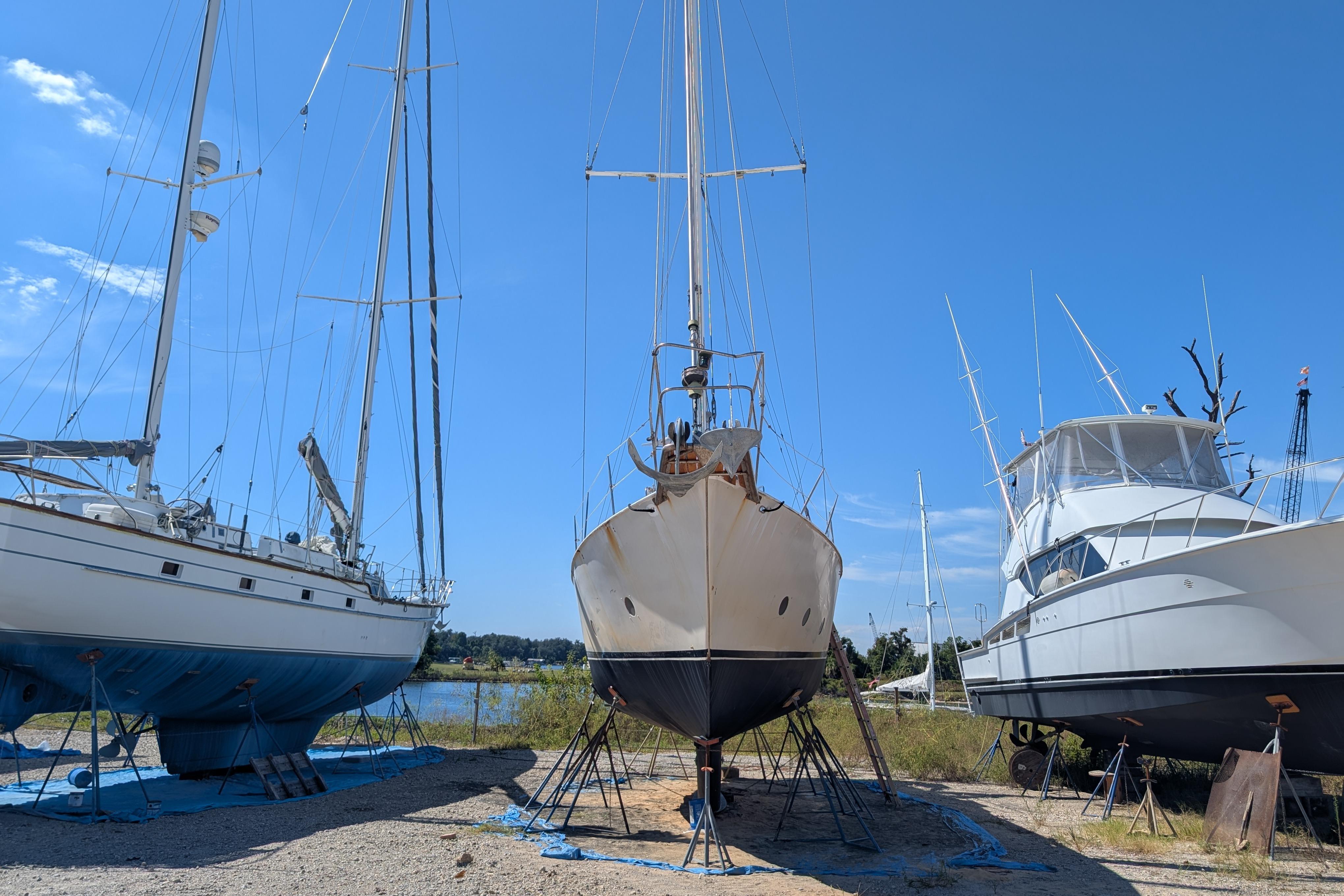 Bruce Bingham Custom 47 Steel Hull 1992 sailboat on land, flanked by other boats.