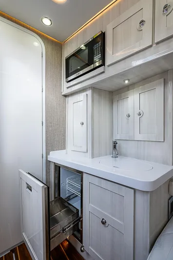  Yacht Photos Pics 2023 HCB 53 Sueños interior with modern kitchenette, featuring white cabinetry and built-in appliances.