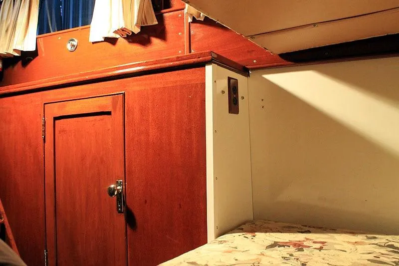 Allez Yacht Photos Pics Interior of a 1930 Chris-Craft Commuter boat with wooden cabinetry and floral bedding.