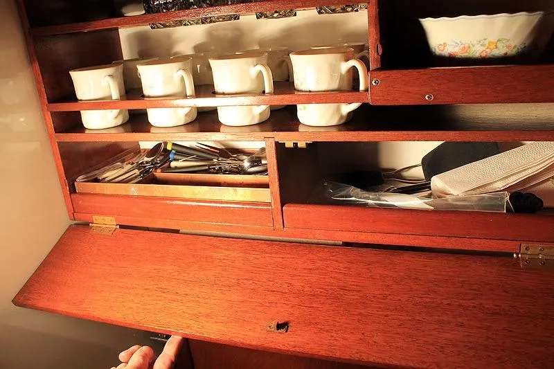 Allez Yacht Photos Pics Wooden cabinet with cups and utensils, part of a 1930 Chris-Craft Commuter boat interior.