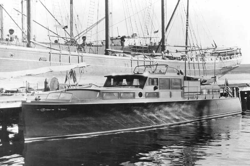Allez Yacht Photos Pics 1930 Chris-Craft Commuter boat docked, with large ships in the background.