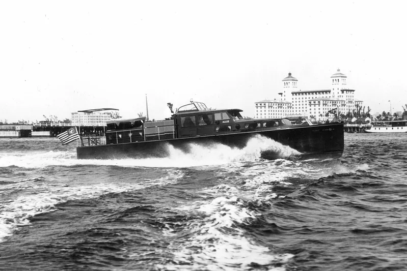 Allez Yacht Photos Pics 1930 Chris-Craft Commuter boat cruising near historic waterfront buildings.