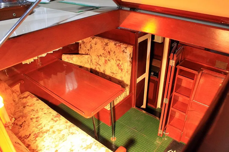 Allez Yacht Photos Pics 1930 Chris-Craft Commuter interior with floral seating, wooden table, and green flooring.
