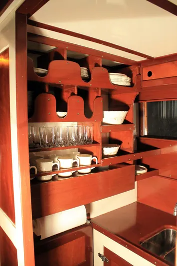 Allez Yacht Photos Pics Interior of 1930 Chris-Craft Commuter with wooden cabinetry and neatly arranged dishware.