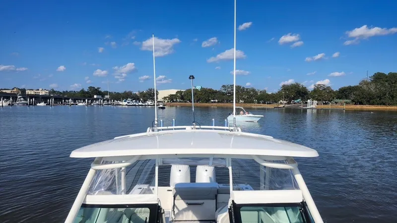  Yacht Photos Pics 2024 Pursuit DC 266 Dual Console boat on calm water under a clear blue sky.